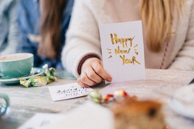 Midsection of girl holding new year card at table