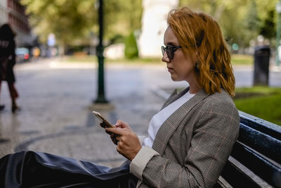 Young woman using mobile phone on bench