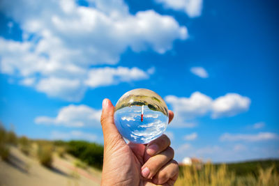 Holding crystal ball against sky and lighthouse