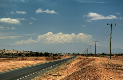 Road leading towards mountains against sky