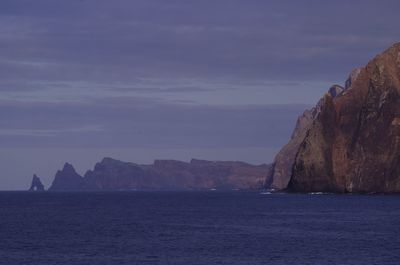Scenic view of sea by mountains against sky