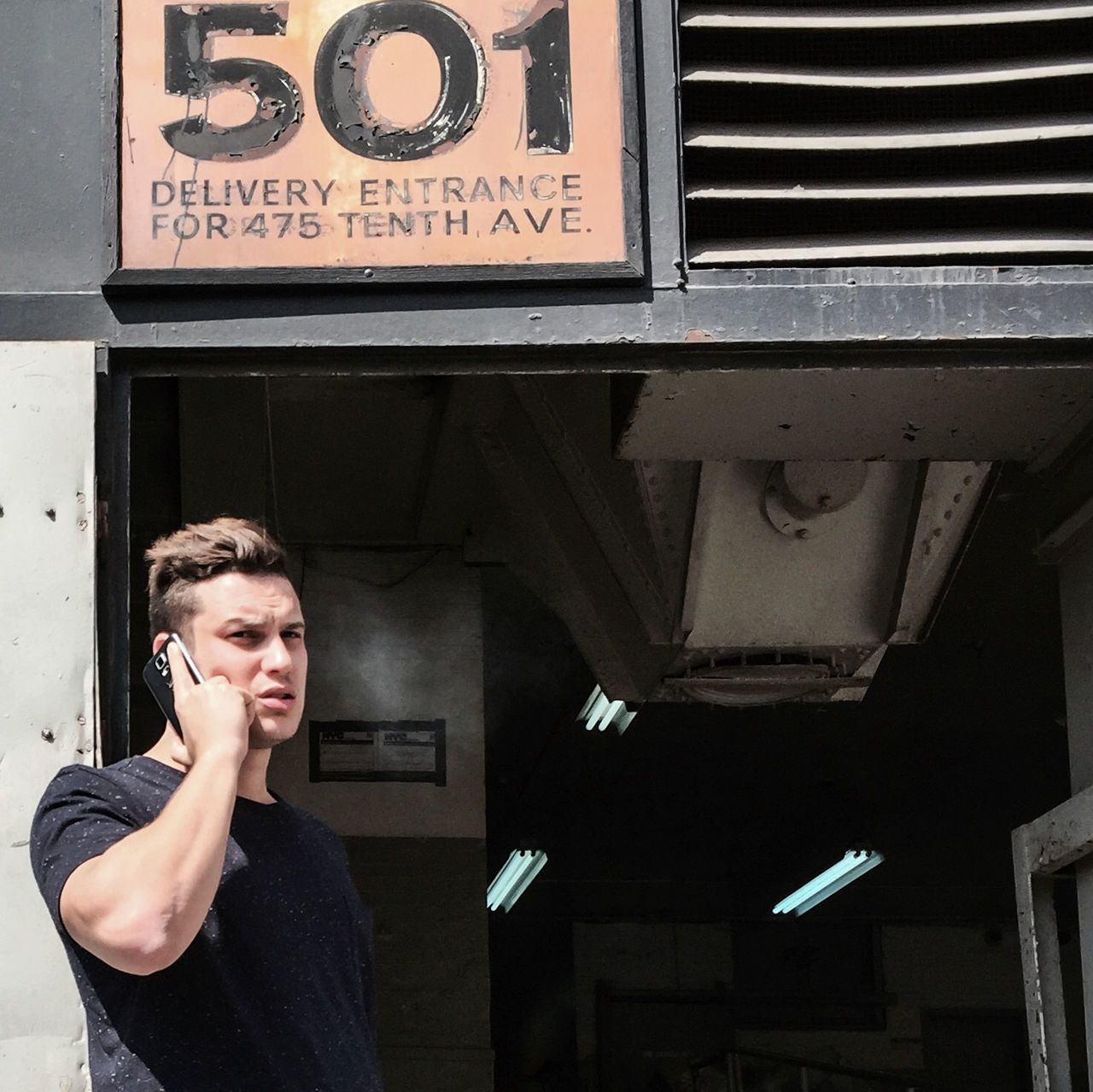 communication, lifestyles, text, young adult, person, leisure activity, young men, standing, casual clothing, wall - building feature, front view, western script, architecture, built structure, three quarter length, portrait, looking at camera, holding