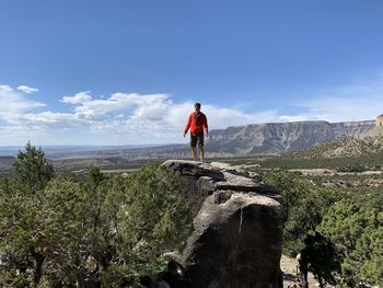 Man standing on rock against sky