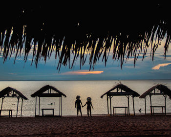 People at beach against sky at sunset