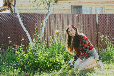 A beautiful woman with long hair and short shorts is working with the ground in the garden