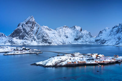 Scenic view of sea and snowcapped mountains against clear blue sky