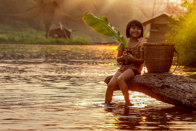 Portrait of smiling girl sitting at riverbank