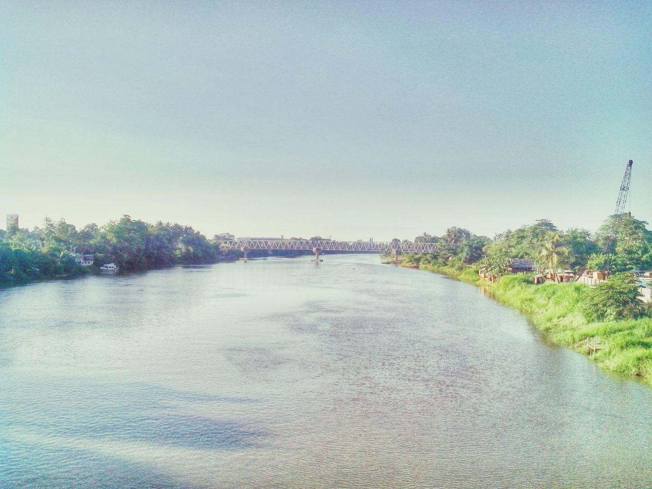 water, clear sky, copy space, built structure, architecture, waterfront, river, connection, tree, bridge - man made structure, building exterior, blue, tranquil scene, tranquility, transportation, nature, scenics, outdoors, bridge, day