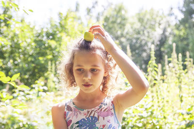 Portrait of young woman blowing bubbles while standing against plants