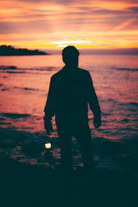 Silhouette man standing at beach during sunset