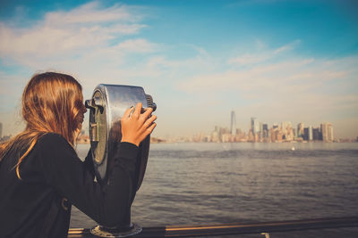 Side view of girl looking through coin-operated binoculars