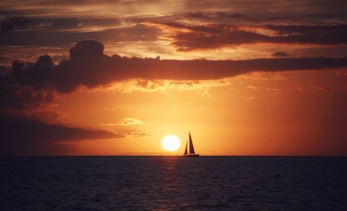 Silhouette of sailboat on sea during sunset