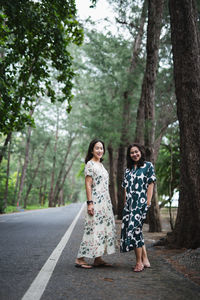 Woman standing on road amidst trees in forest