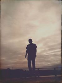 Rear view of silhouette man standing on landscape against sky
