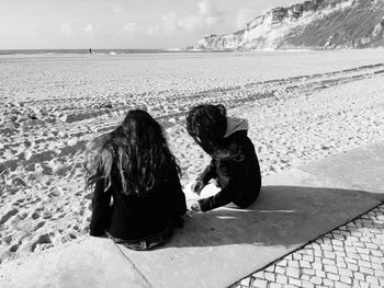 Friends sitting at sandy beach