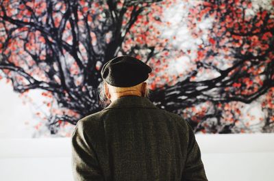 Rear view of man standing on field against trees