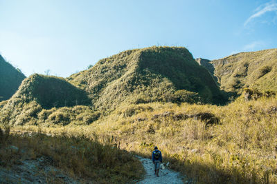 Rear view of man walking on mountain road