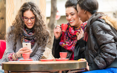 Happy young woman using phone while standing in winter