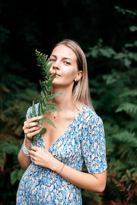 Portrait of young woman standing against plants