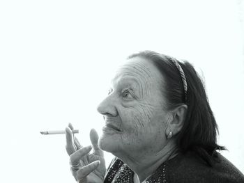 Close-up of woman smoking cigarette against white background