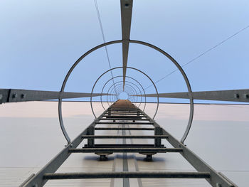 Low angle shot of metal ladder against clear blue sky