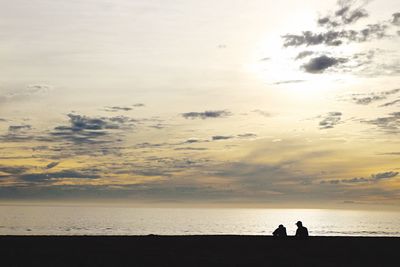 Silhouette people on beach against sky during sunset