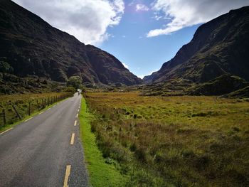 Scenic view of road by mountains against sky