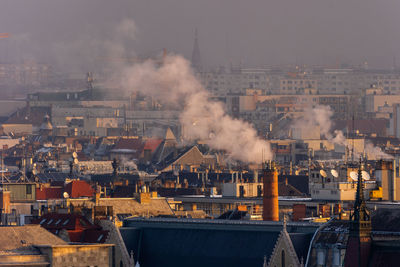 Smoke emitting from factory against sky