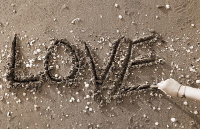 Cropped hand writing love text at beach