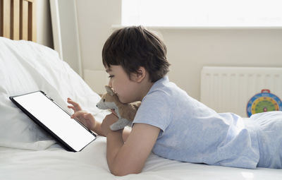 Boy using mobile phone on bed at home