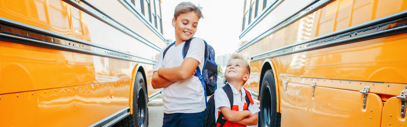 Smiling boys standing amidst school bus