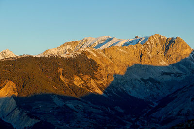 Scenic view of snowcapped mountains against clear blue sky