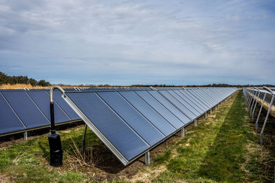 Solar panels on field against sky