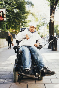 Front view of disabled man on wheelchair at sidewalk in city