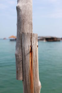 Close-up of wooden post at beach against sky