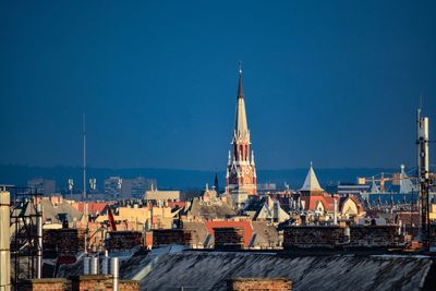 Buildings in city against clear blue sky