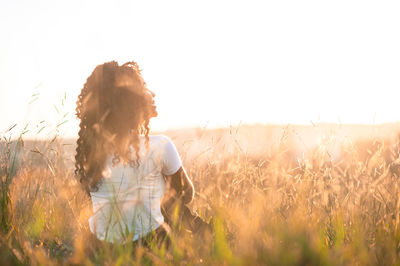 Young woman standing on field against sky