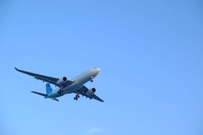 Low angle view of airplane against clear blue sky