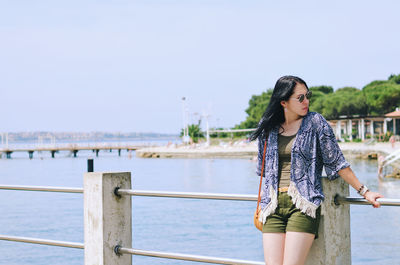 Portrait of young woman standing against sea