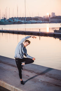 Side view of man standing on railing against sky