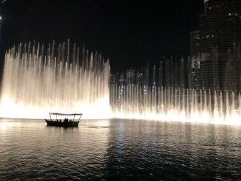 Scenic view of sea against illuminated buildings at night