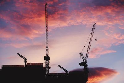 Low angle view of silhouette crane against sky during sunset