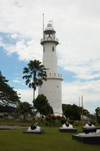 Lighthouse by building against sky