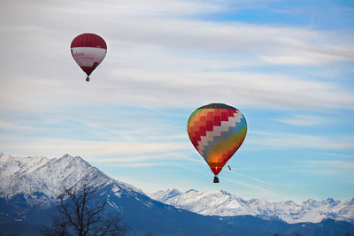 Hot air balloon flying over snowcapped mountains against sky