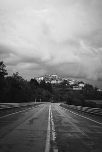 Road leading towards city against sky