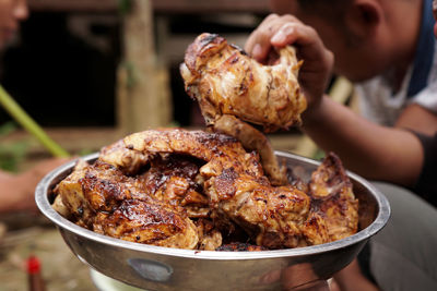 Close-up of hand holding meat on barbecue grill