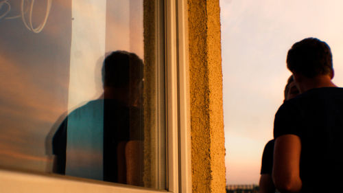 Low angle view of men talking while standing by window with reflection