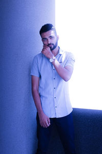 Portrait of young man standing against wall