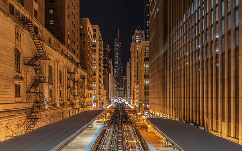 High angle view of railroad station platform amidst illuminated city at night