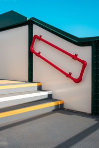 A minimal photo of a clear blue sky and colourful steps and handrail.